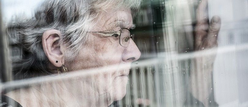 Seniorin sieht aus dem Fenster